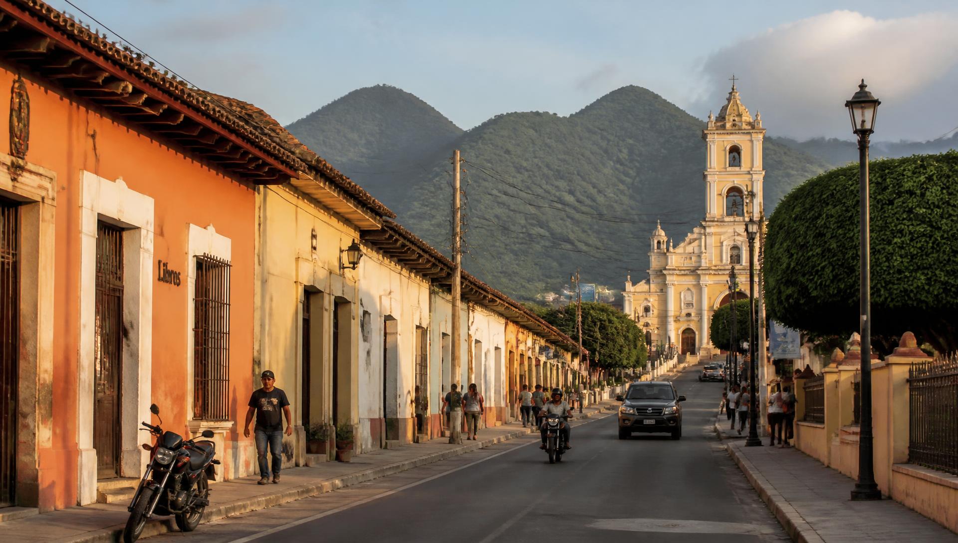 Street in Zaragoza at golden hour with green hills behind the town